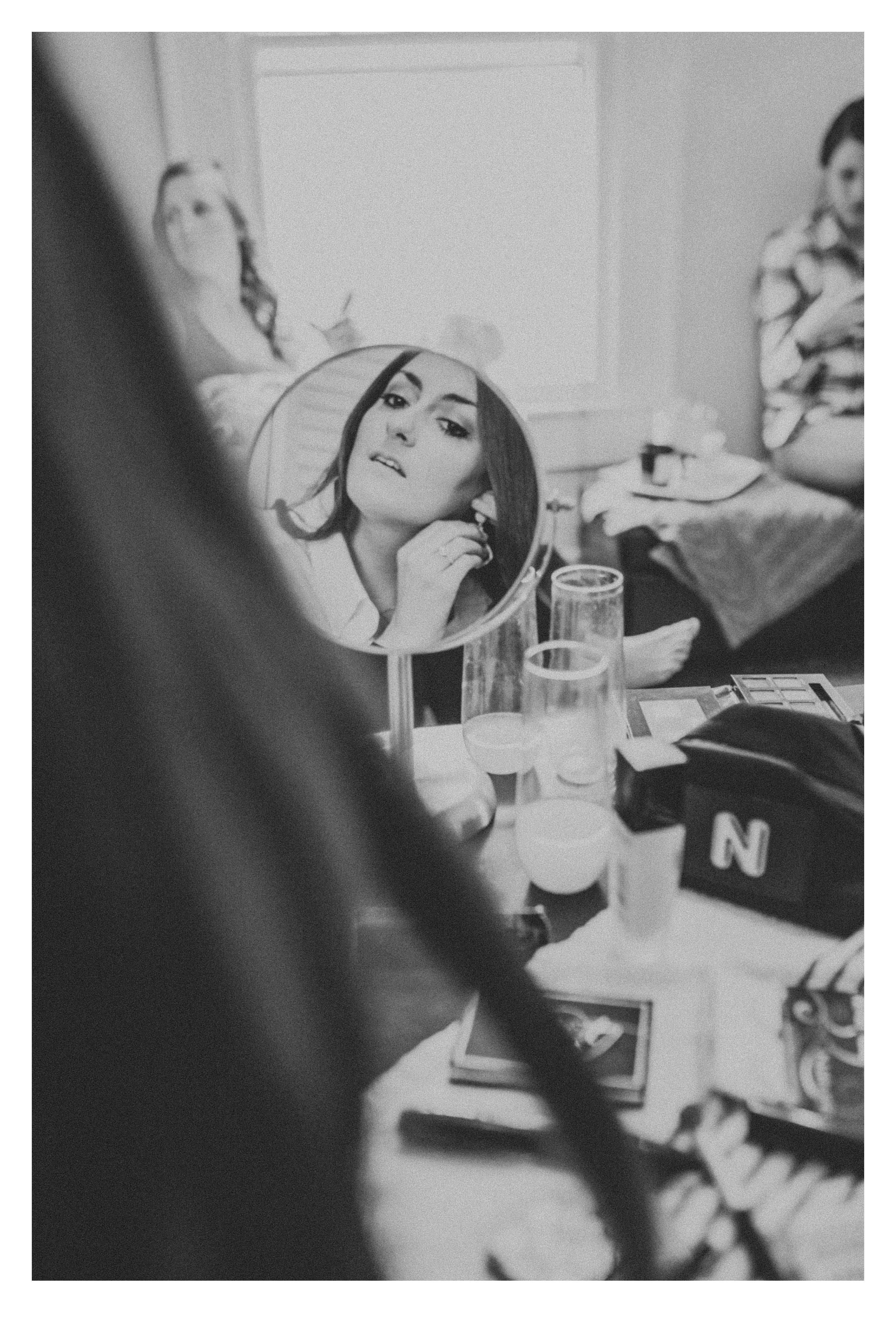 Black and White photo of bride putting on earrings