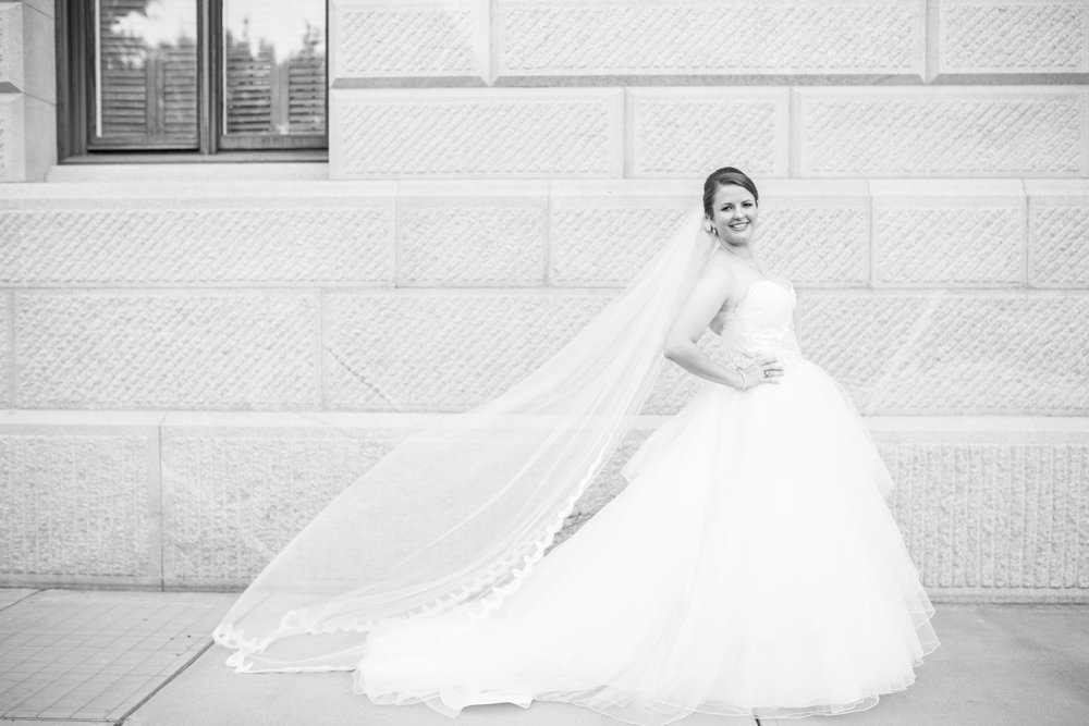 B&W Photo of bride by Statehouse Wall