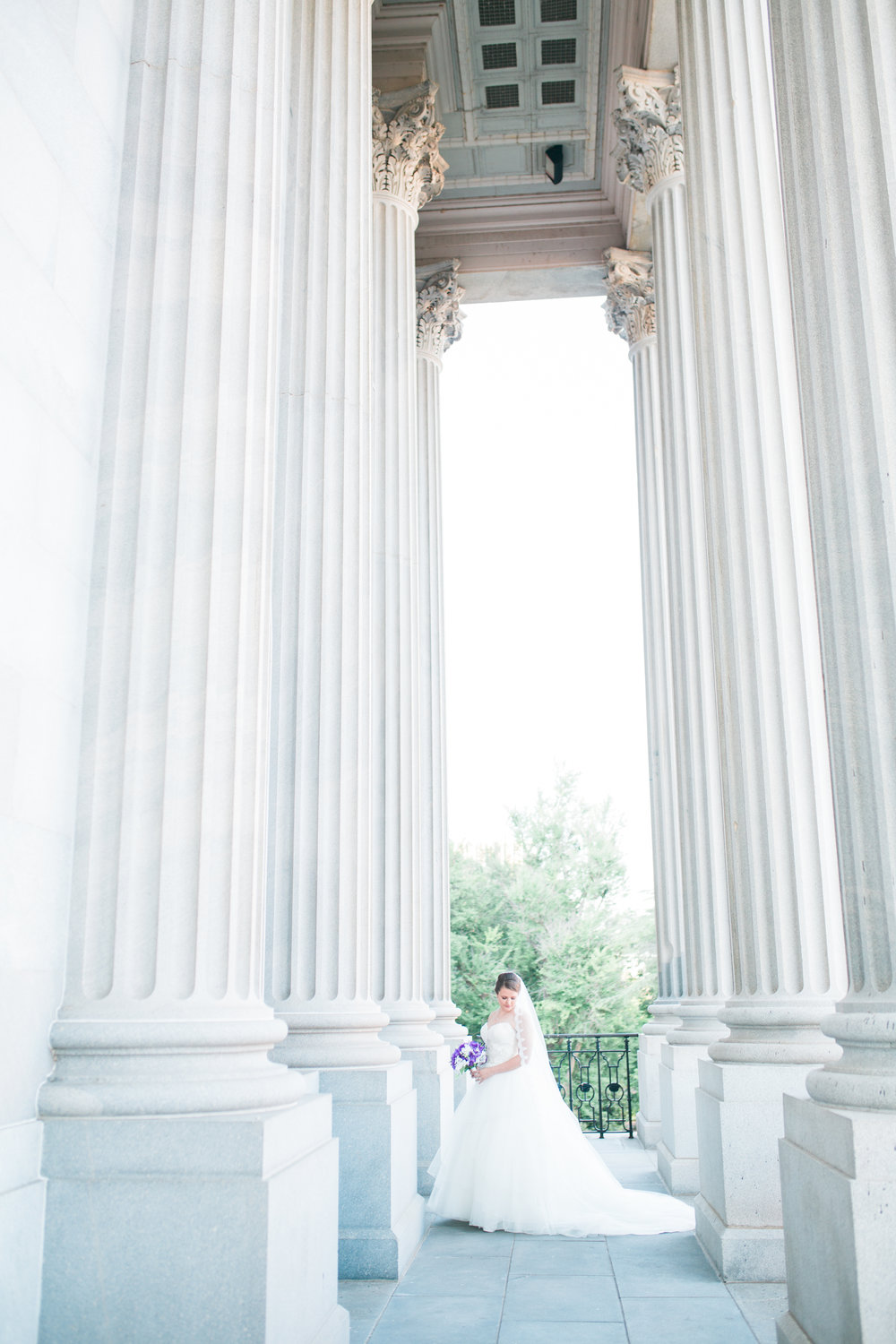 Bride holding flowers by statehouse columns
