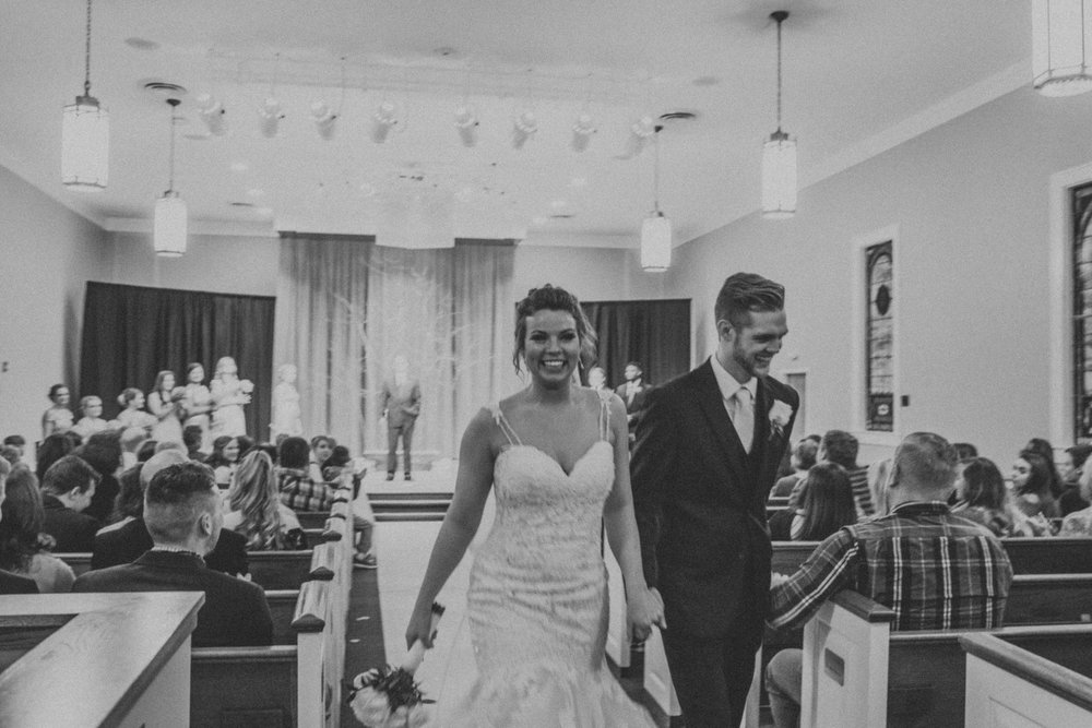 B&W photo of bride and groom leaving the alter