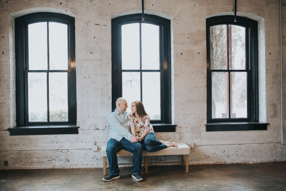 Couple sitting in rustic room during their engagement photo session