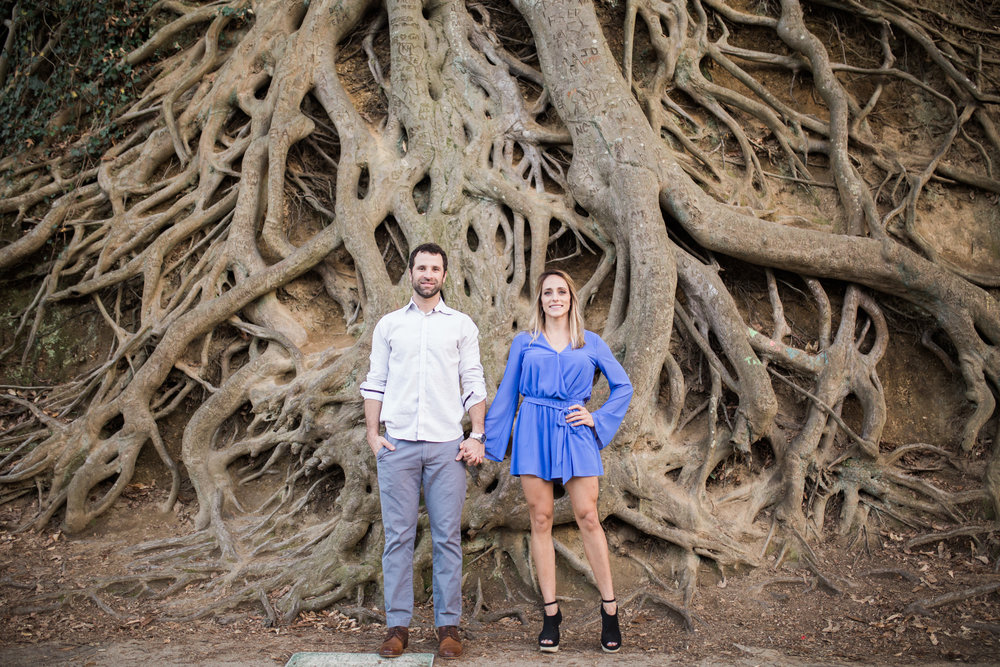 Holding Hands and looking serious in front of tree roots