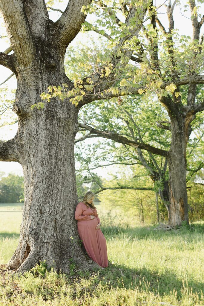 Future Mom leaning against tree for her maternity photo shoot.